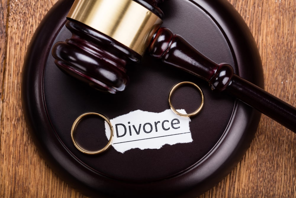 How to File for Divorce in British Columbia portrayed by a gavel, two wedding rings and a piece of paper with the words "divorce".