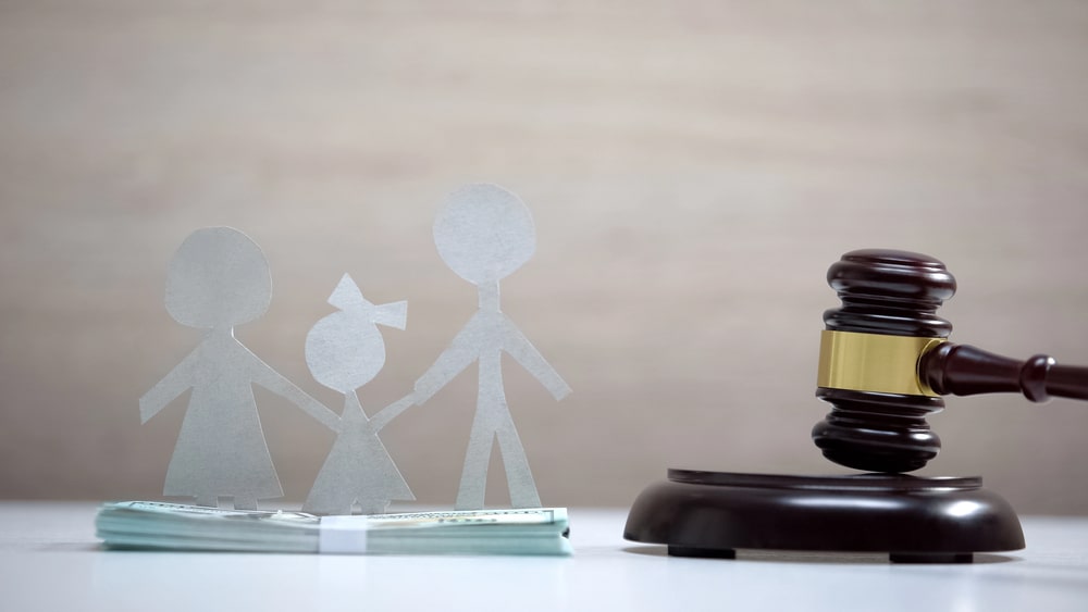 How to terminate your spousal support in British Columbia portrayed by a gavel, a stack of money and a separating family caricature standing on top of the money.